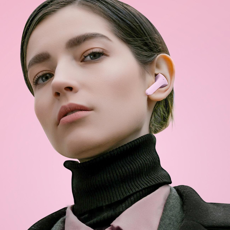 Į ausis įdedamos TWS Bluetooth belaidės ausinės, rožinės spalvos